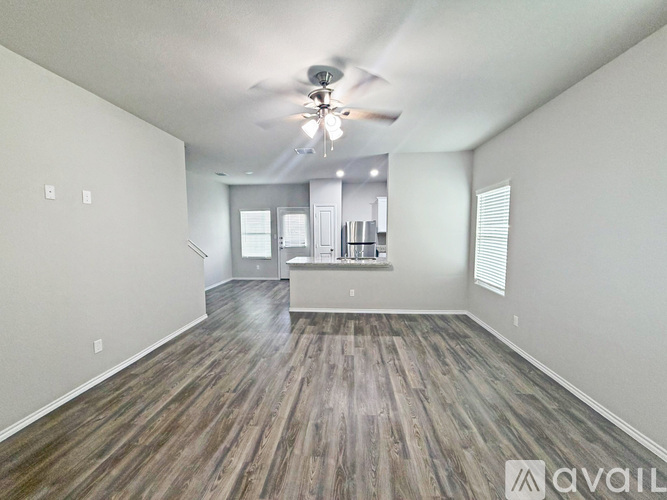 A spacious room with wood flooring and a ceiling fan.