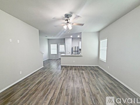 A spacious room with wood flooring and a ceiling fan.