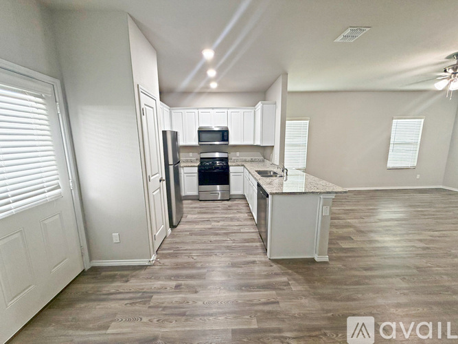A kitchen with white cabinets and a wooden floor.