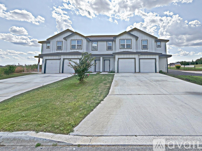 A large, modern house with a grey roof and a long driveway.