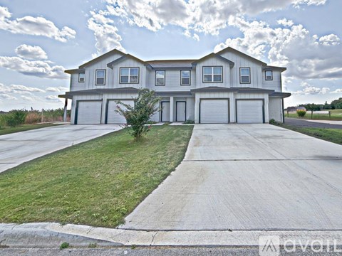 A large, modern house with a grey roof and a long driveway.