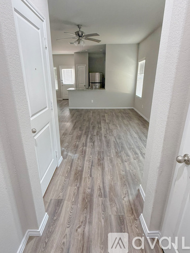 A spacious room with wood flooring and a ceiling fan.