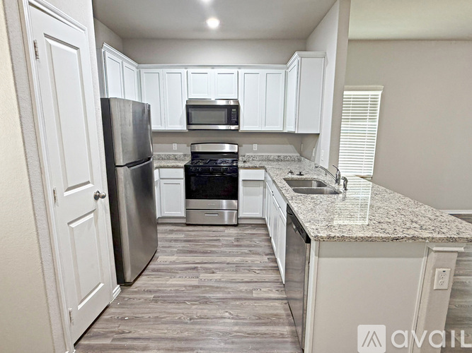 A kitchen with white cabinets and a granite countertop.