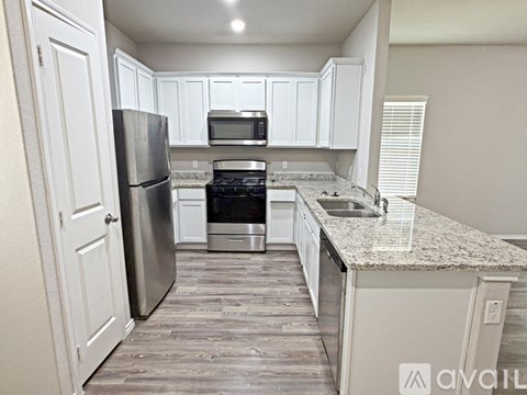 A kitchen with white cabinets and a granite countertop.