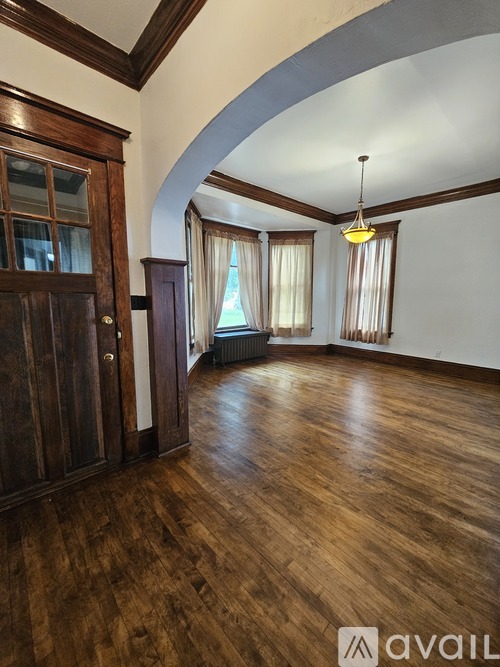 A room with wooden floors and a large arched doorway.