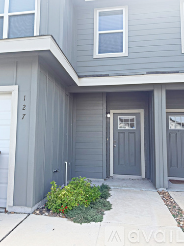 A grey house with a white door and windows.