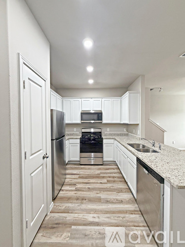 A kitchen with white cabinets and a wooden floor.