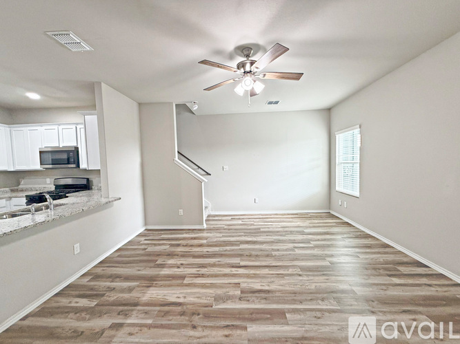 A spacious living room with a wood floor and a ceiling fan.