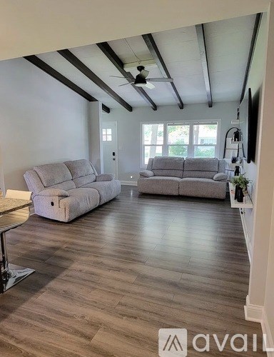 A living room with two grey couches and a wooden floor.