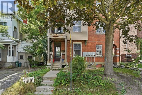 A tree in front of a brick building with a sign that says RE/MAX Delta Realty Brokerage.