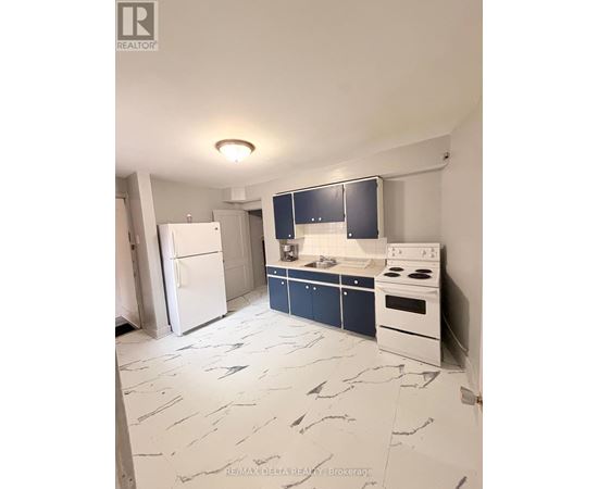 A kitchen with a white fridge, white stove, and blue cabinets.