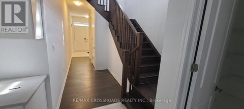 A hallway with a staircase and a door at the end.