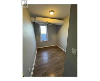 A room with a window and a wooden floor.