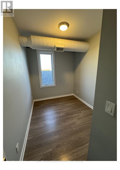 A room with a window and a wooden floor.