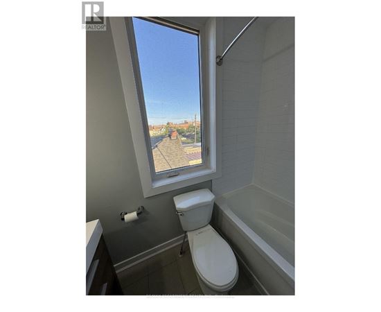 A bathroom with a toilet, a bathtub, and a window.