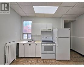A white kitchen with a refrigerator, sink, and stove.