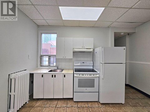 A white kitchen with a refrigerator, sink, and stove.