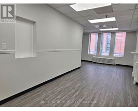 A room with a white wall and a window with a view of a red building.