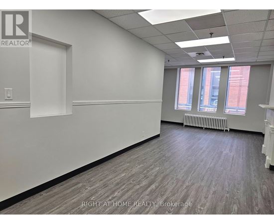 A room with a white wall and a window with a view of a red building.