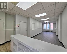 A white reception desk in an office space with a skylight.