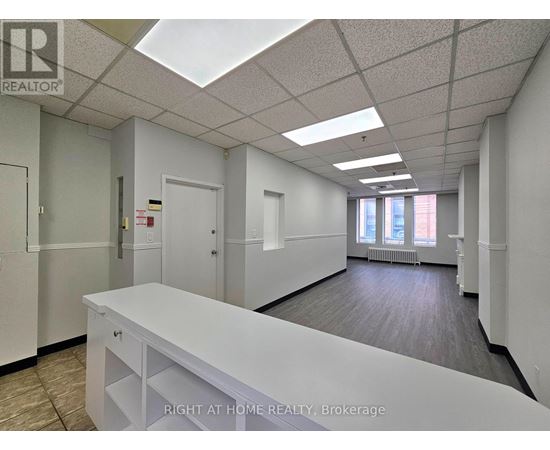 A white reception desk in an office space with a skylight.
