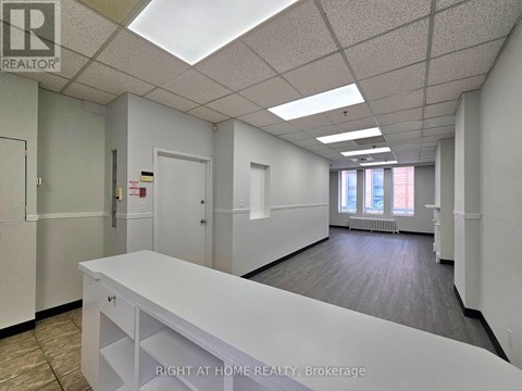 A white reception desk in an office space with a skylight.