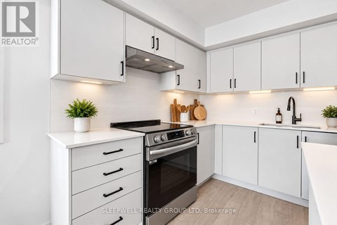 A modern kitchen with white cabinets and a black stove top.