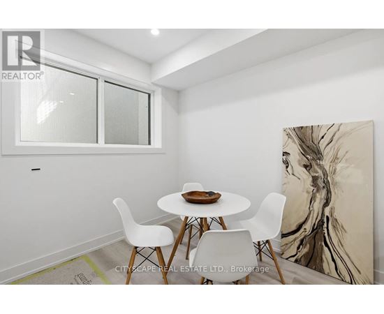 A dining room with a white table and chairs and a large painting on the wall.