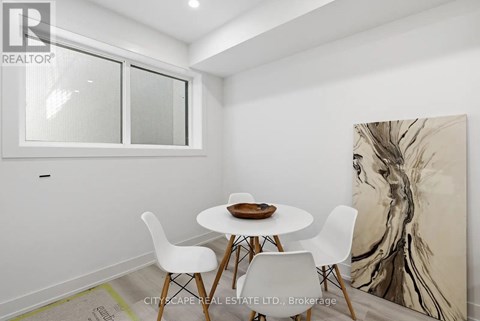 A dining room with a white table and chairs and a large painting on the wall.