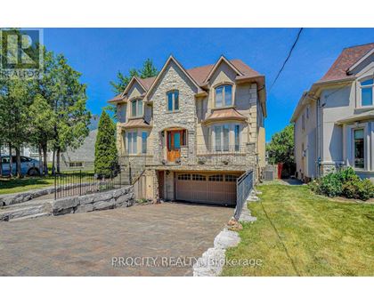 A large, two-story house with a stone facade and a garage is for sale.