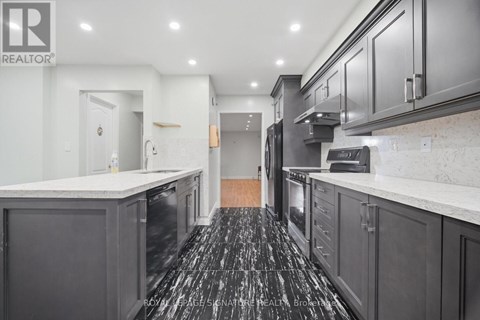 A kitchen with black cabinets and a marble counter top.