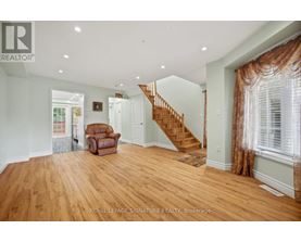 A spacious room with wooden floors and a staircase.