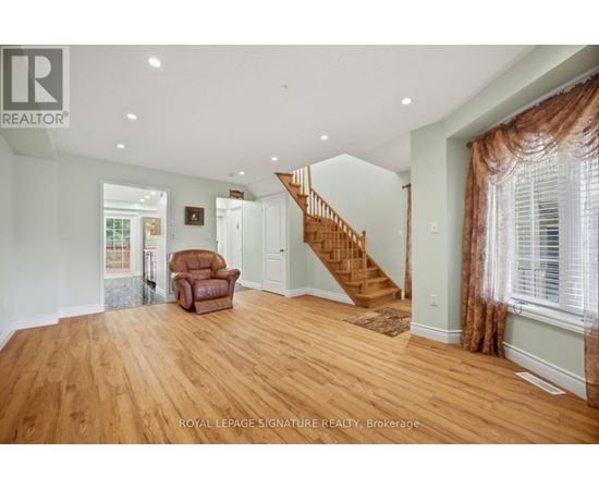 A spacious room with wooden floors and a staircase.