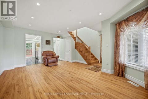 A spacious room with wooden floors and a staircase.
