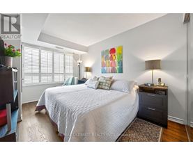 A bedroom with a large bed, a nightstand with a lamp, and a painting on the wall.