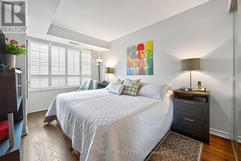 A bedroom with a large bed, a nightstand with a lamp, and a painting on the wall.
