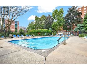 A large outdoor swimming pool surrounded by trees and chairs.