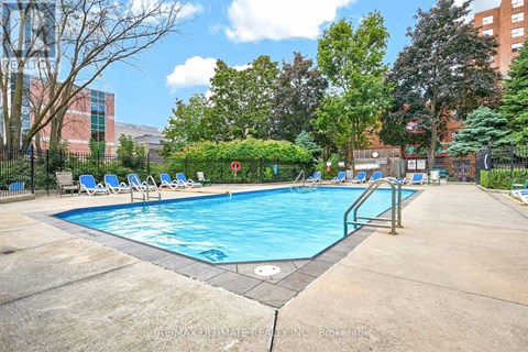 A large outdoor swimming pool surrounded by trees and chairs.