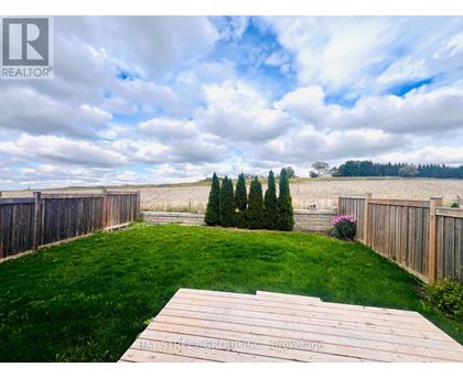 A wooden deck overlooks a grassy backyard with a fence and trees.