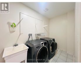A laundry room with a white sink and two washing machines.