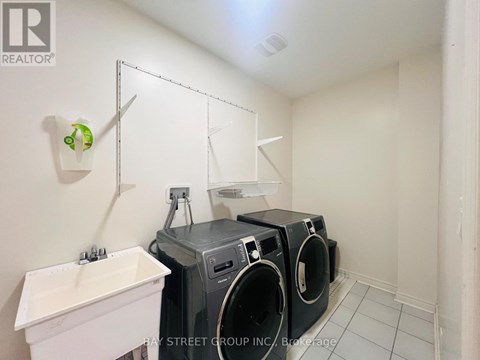 A laundry room with a white sink and two washing machines.