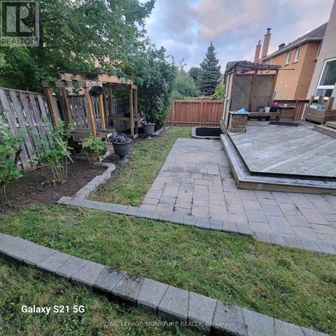 A backyard with a wooden deck and a small gazebo.