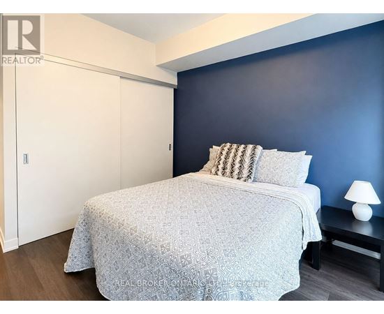 A bedroom with a bed, nightstand, and lamp.