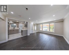 A spacious room with wooden floors and a large window.