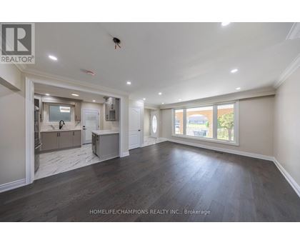 A spacious room with wooden floors and a large window.
