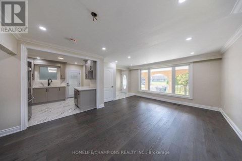 A spacious room with wooden floors and a large window.