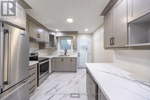 A modern kitchen with stainless steel appliances and marble countertops.