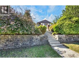 A stone wall with a staircase leading to a house.