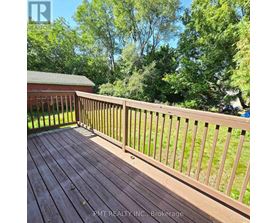 A wooden deck with a railing and trees in the background.