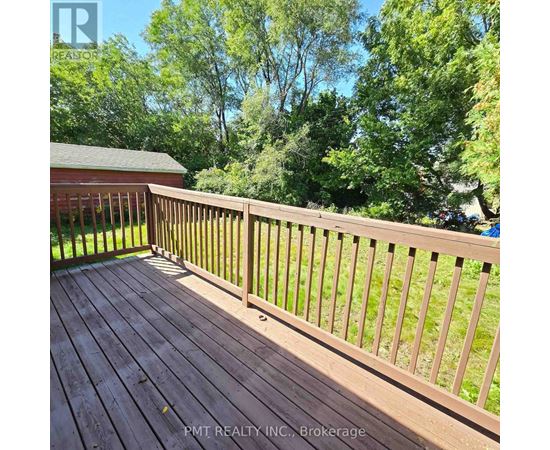 A wooden deck with a railing and trees in the background.